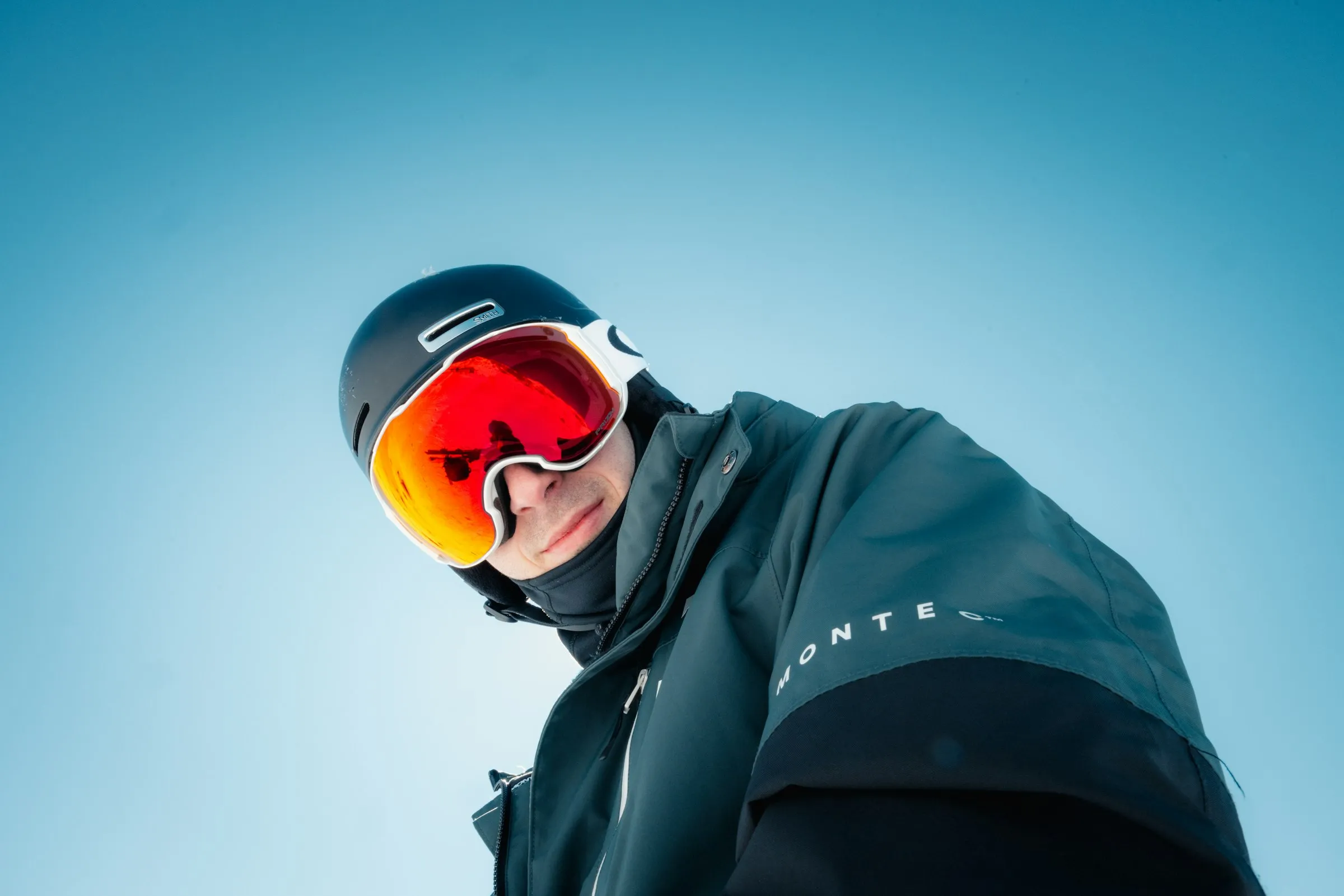 戴安全帽、雪鏡與脖圍，穿著滑雪外套的單板玩家